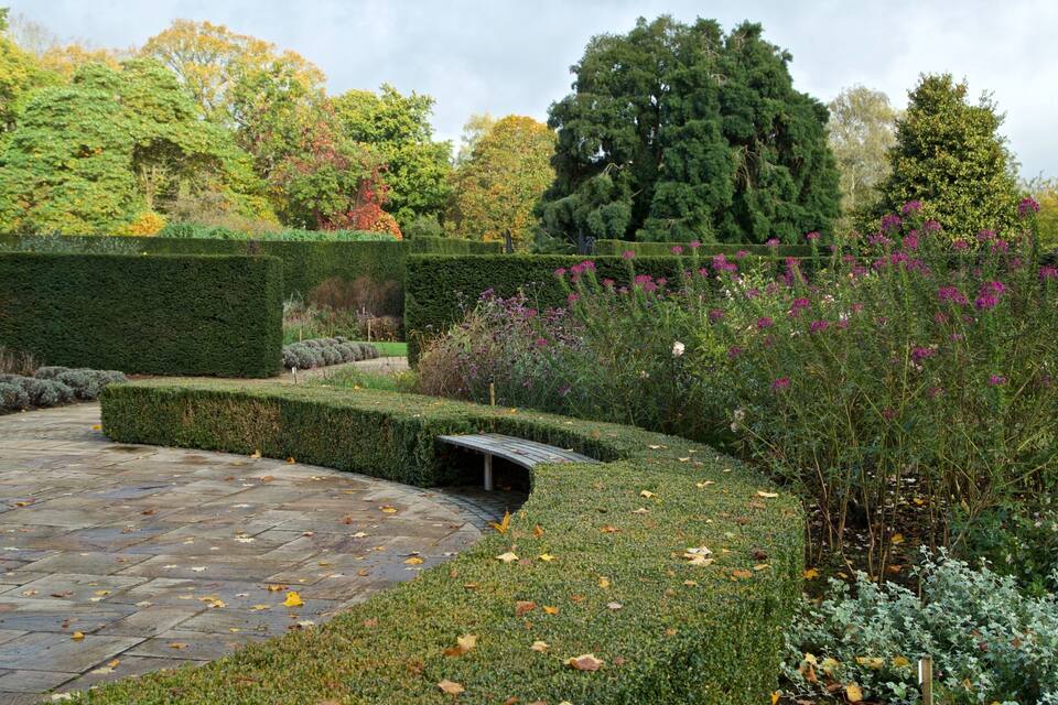 A landscaped garden with a stone pathway, neatly trimmed hedges, and flowering plants.