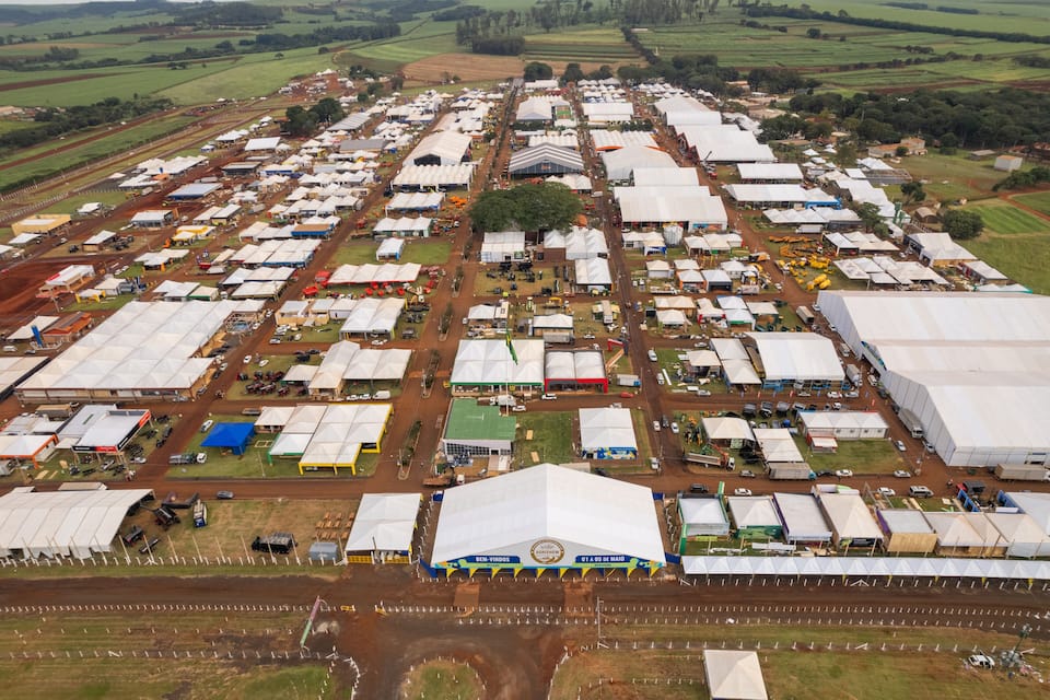 An aerial view of a large agricultural fair with numerous tents and vehicles.