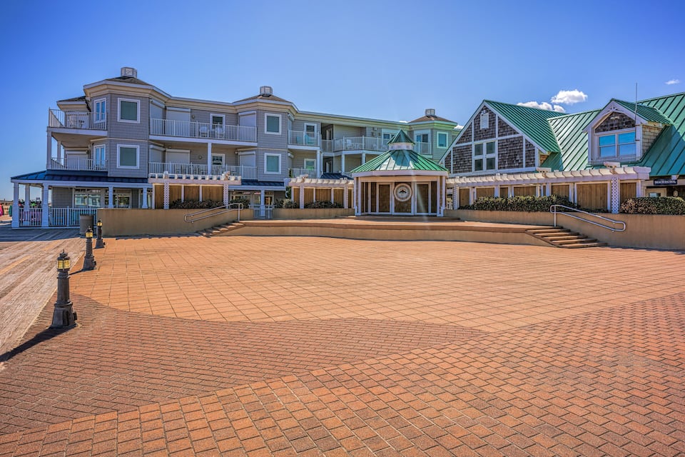 Een resort aan het water, met een groot gebouw, een prieel en een pad van bakstenen.