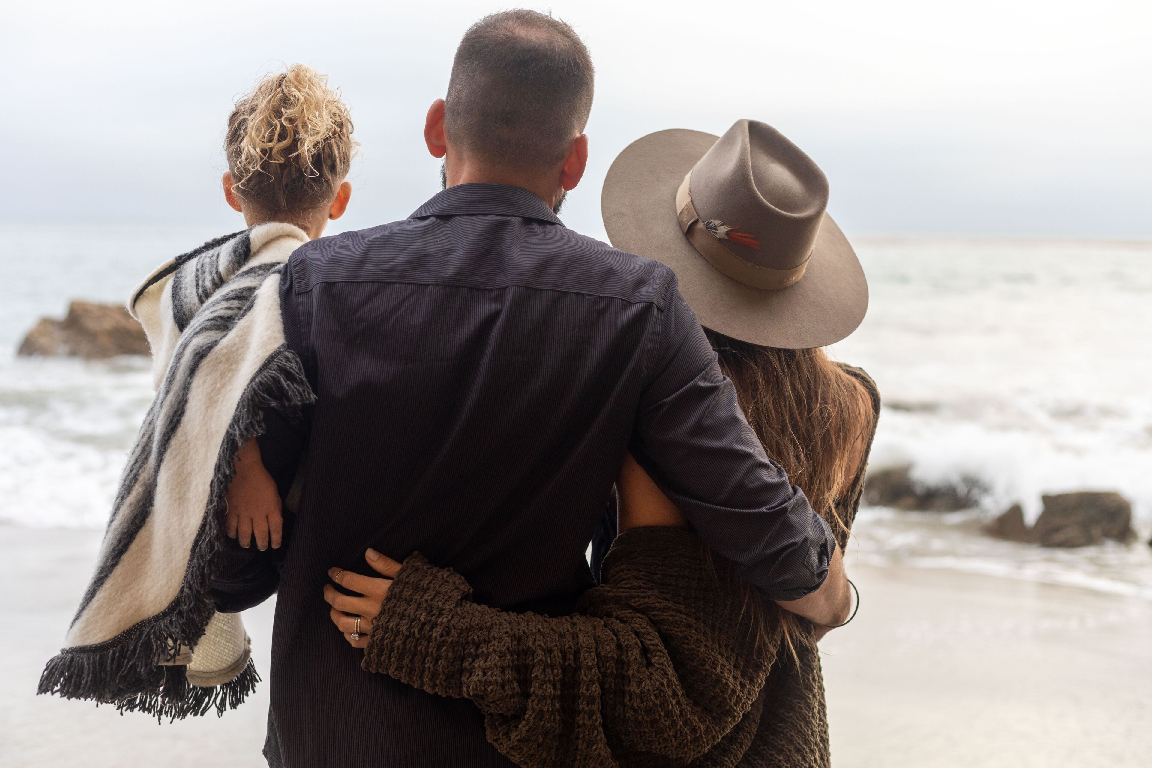 Family embraces on beach.