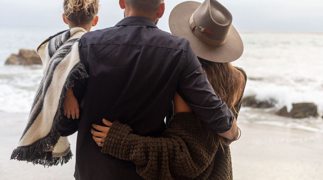 Family embraces on beach.