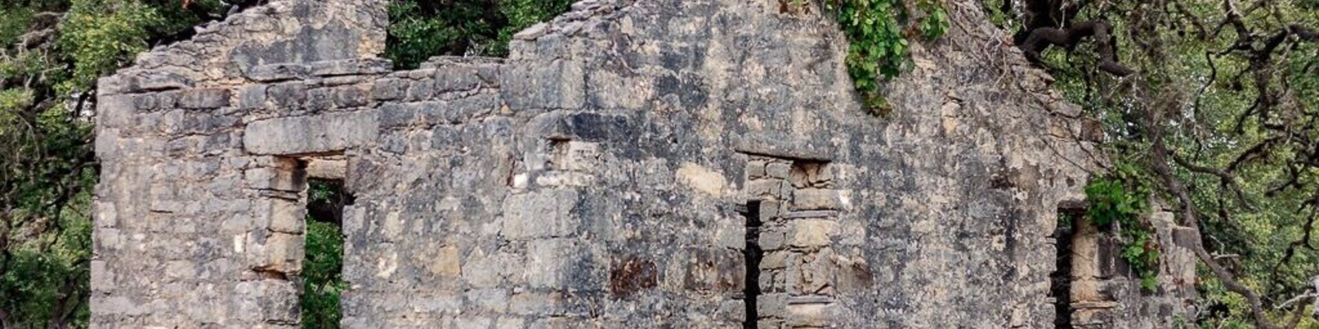 An ancient stone structure with visible openings and overgrown vegetation.