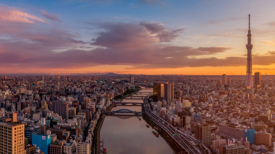 Paisagem urbana com um rio, pontes e uma torre imponente.