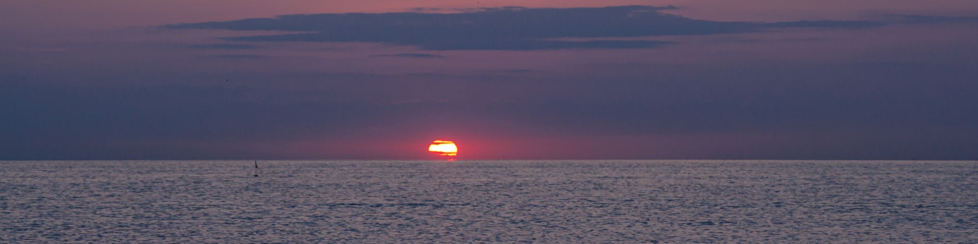 Un atardecer sobre un mar tranquilo con olas suaves.