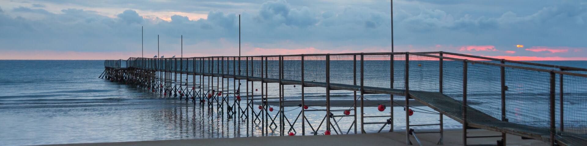 dock at rivazzurra beach (Rimini/Italy) in the morning light; dramatic ocean sunrise landscape