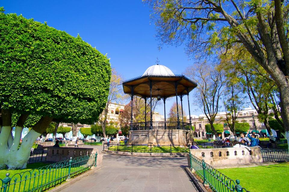 A park with a gazebo, trees, and a clear blue sky.