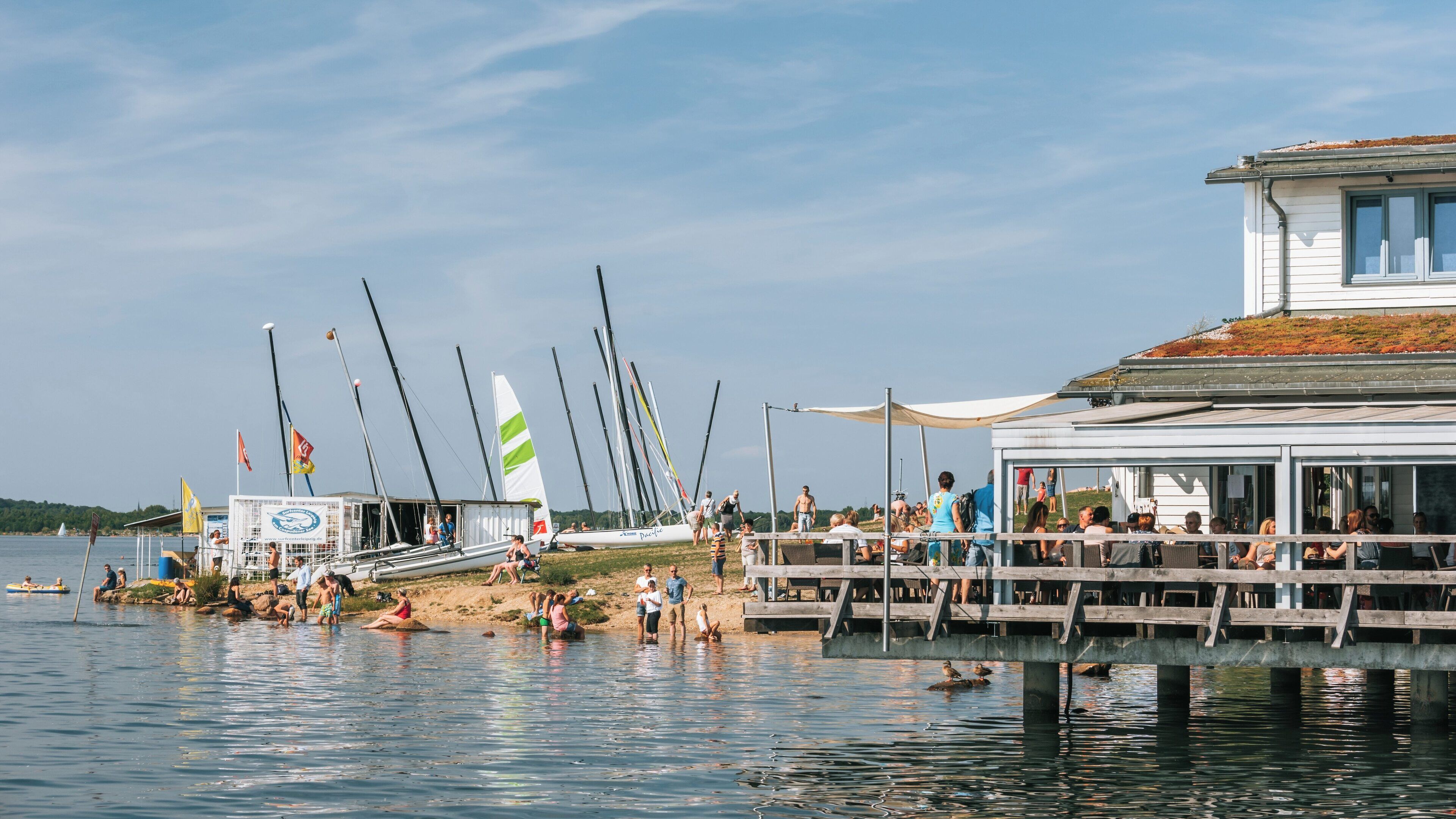 Warm summer day at Cospudener Lake in Leipzig with people enjoying water activities and relaxing by the shore