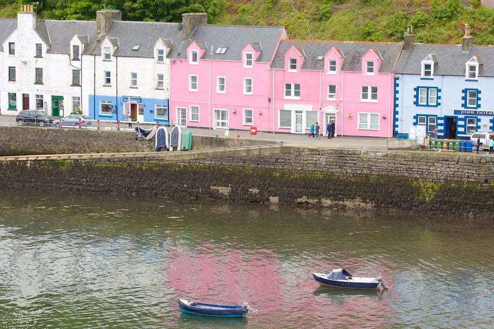A waterfront with colorful buildings, a stone wall, and two boats on the water.