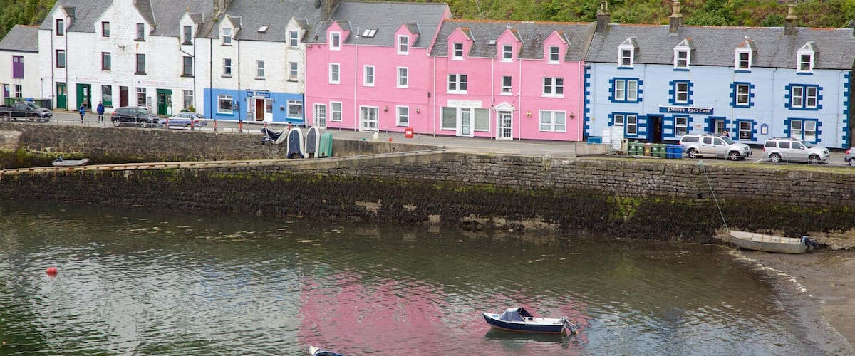 A waterfront with colorful buildings, a stone wall, and boats.