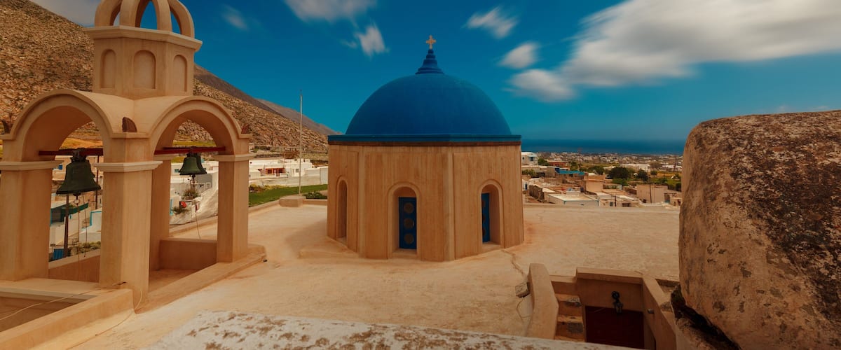 A church with a blue dome and a bell tower, set against a clear blue sky.