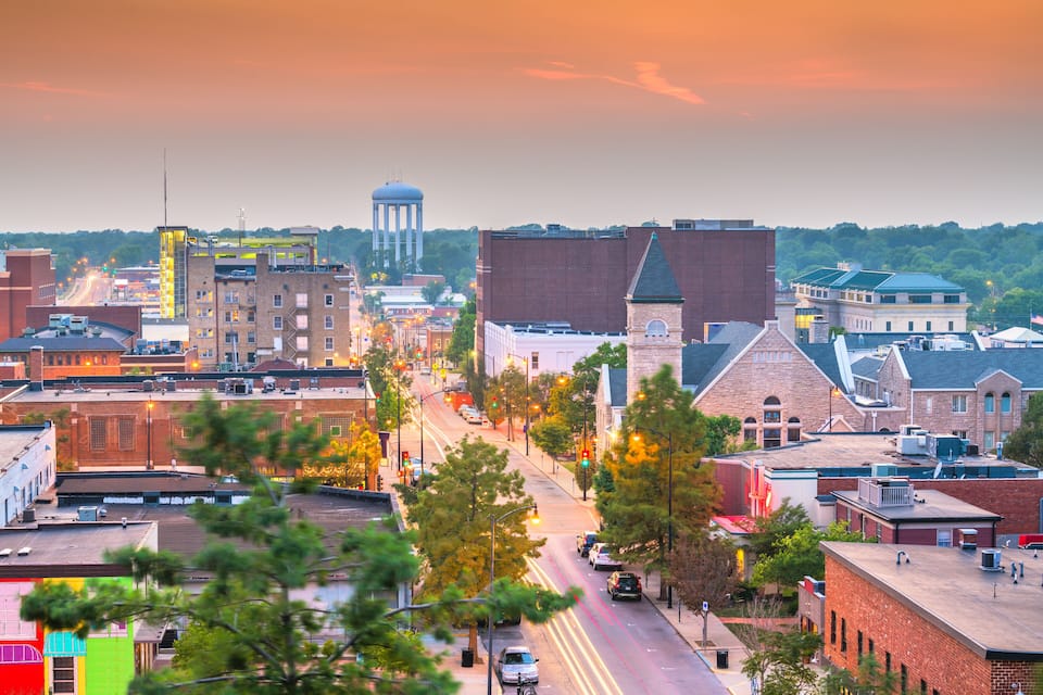 A cityscape with a prominent water tower, a church with a steeple, and a mix of commercial and residential buildings.
