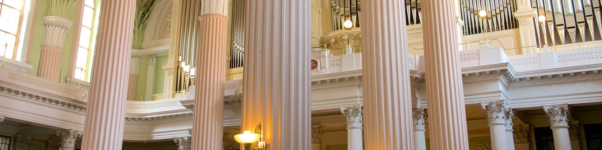 Ornate columns, a grand organ, and a high ceiling with intricate designs.
