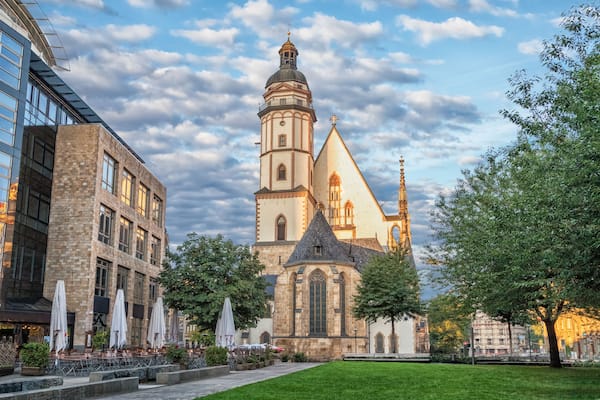 Une église historique dotée d’un clocher imposant, un bâtiment moderne aux grandes fenêtres et une cour bien entretenue avec des espaces de repos en plein air.