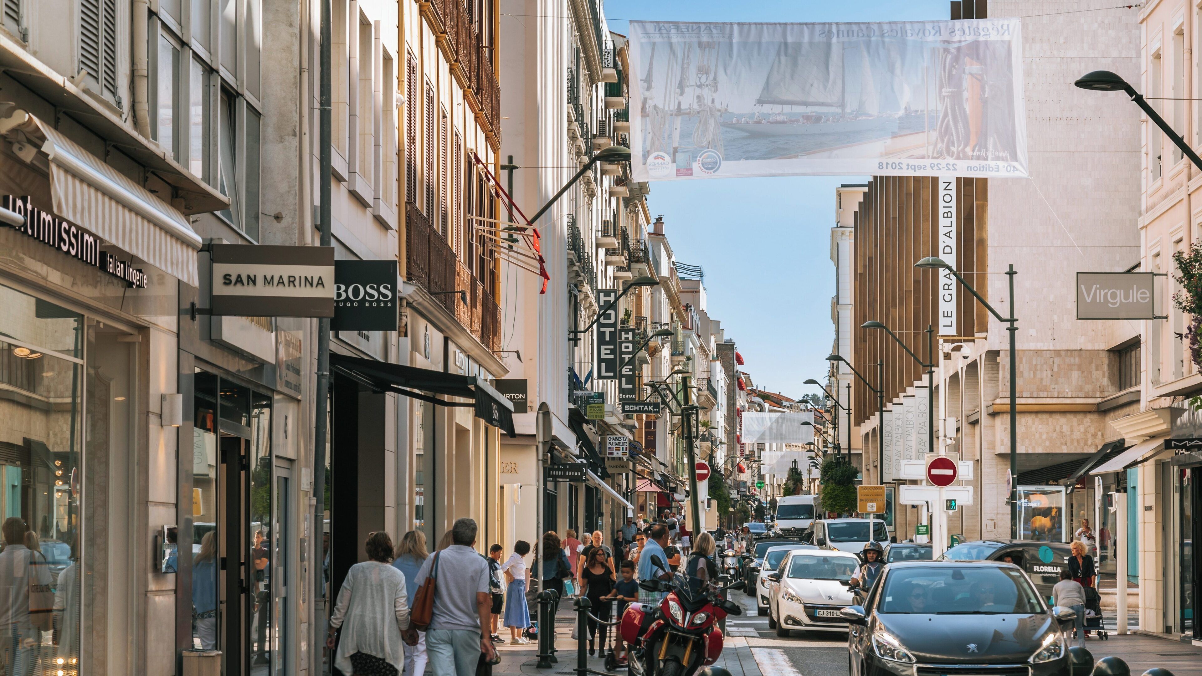 Busy Rue d'Antibes in Cannes showcases vibrant city life with shops, pedestrians, and vehicles on a sunny day in Provence-Alpes-Côte d'Azur, France