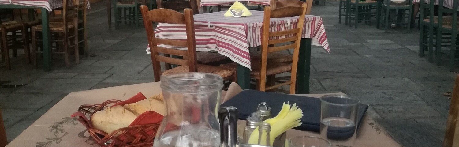 Un área de comedor al aire libre con mesas, sillas y una variedad de platos que incluyen verduras y pan.