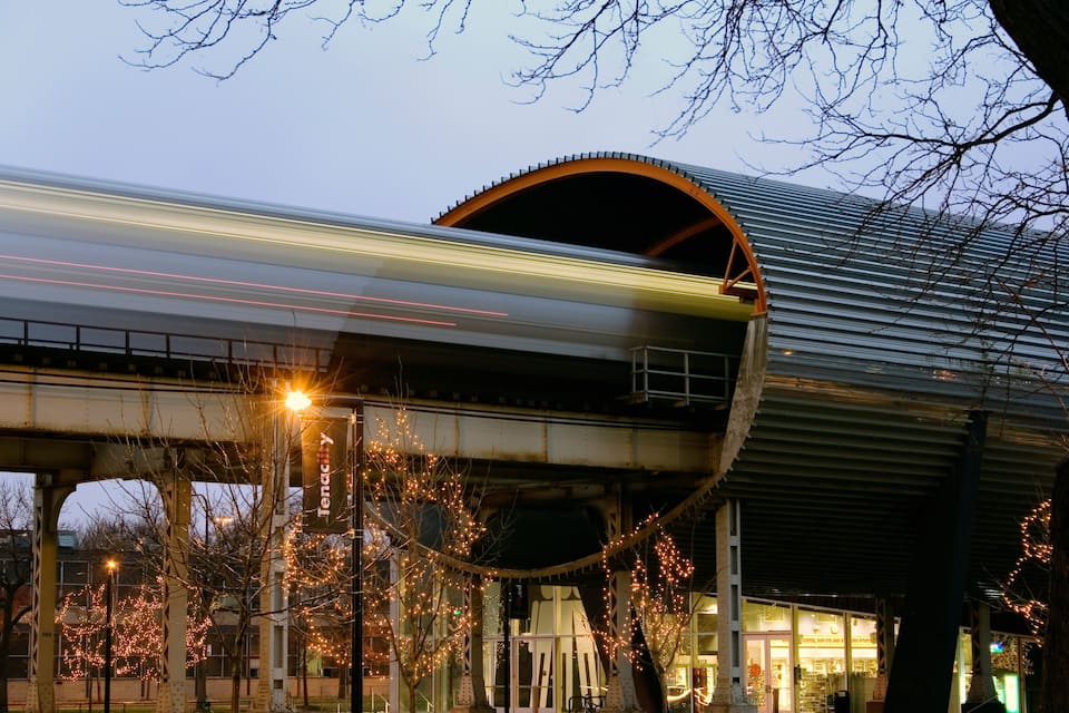 Um trem passando por um túnel com teto curvo e luzes de corda.