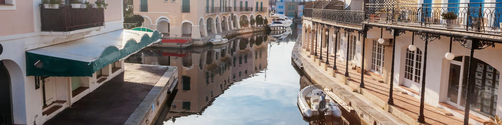 A canal with buildings on either side, including a white building with a green awning and a yellow building with blue doors.