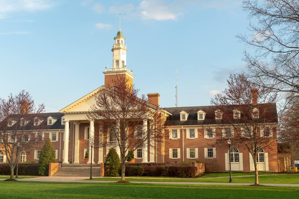 A large brick building with a prominent clock tower and columns.