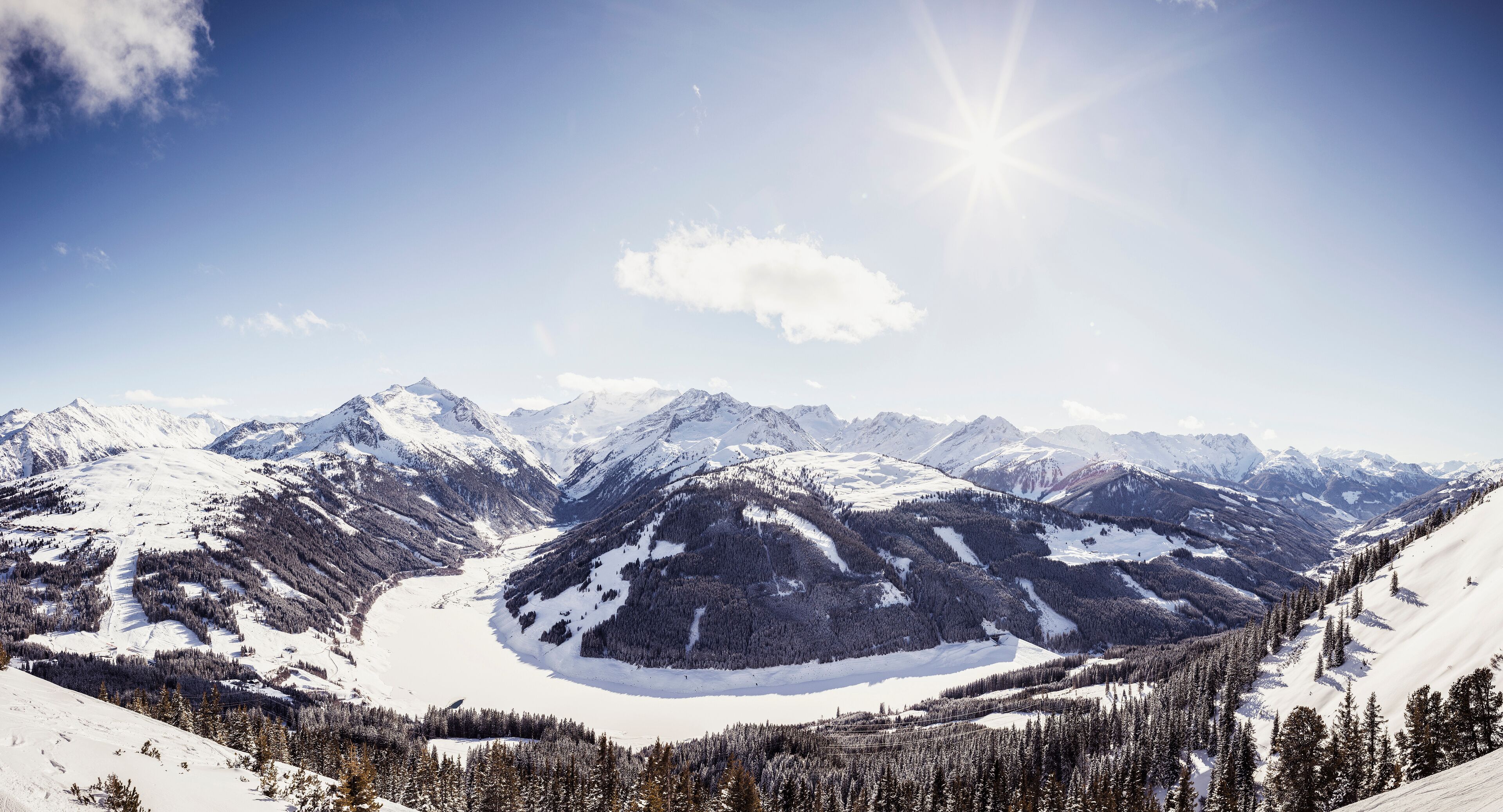 A snow-covered mountain range with a glacier and dense forests.