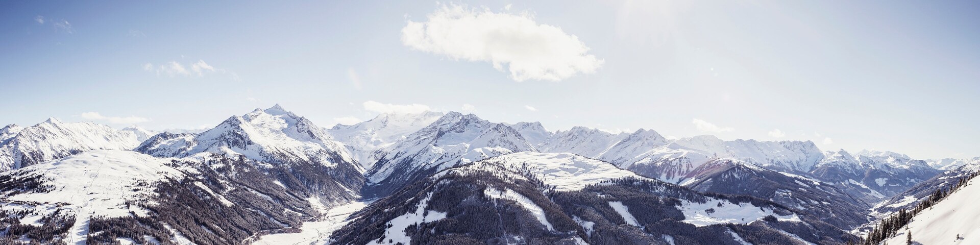A snow-covered mountain range with a glacier and dense forests.