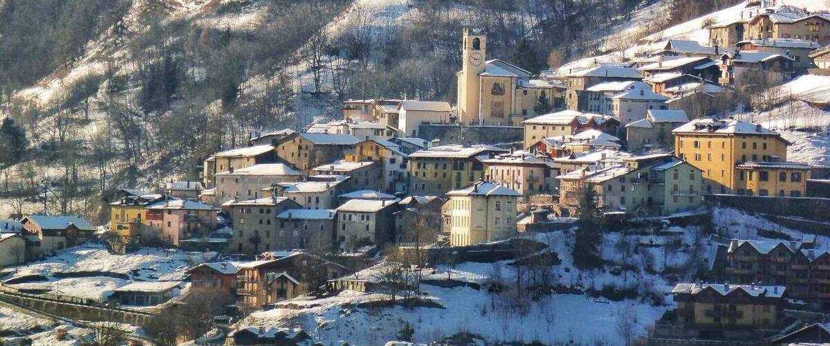 A snow-covered village nestled in a valley with a prominent church tower.