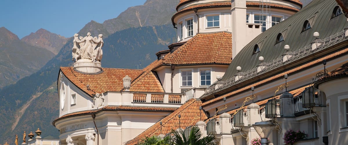 A historic building with a dome and statues, surrounded by mountains.