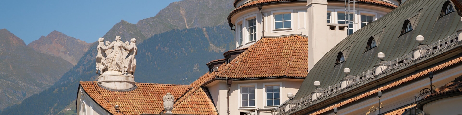 Um edifício histórico com cúpula e estátuas, rodeado por montanhas.