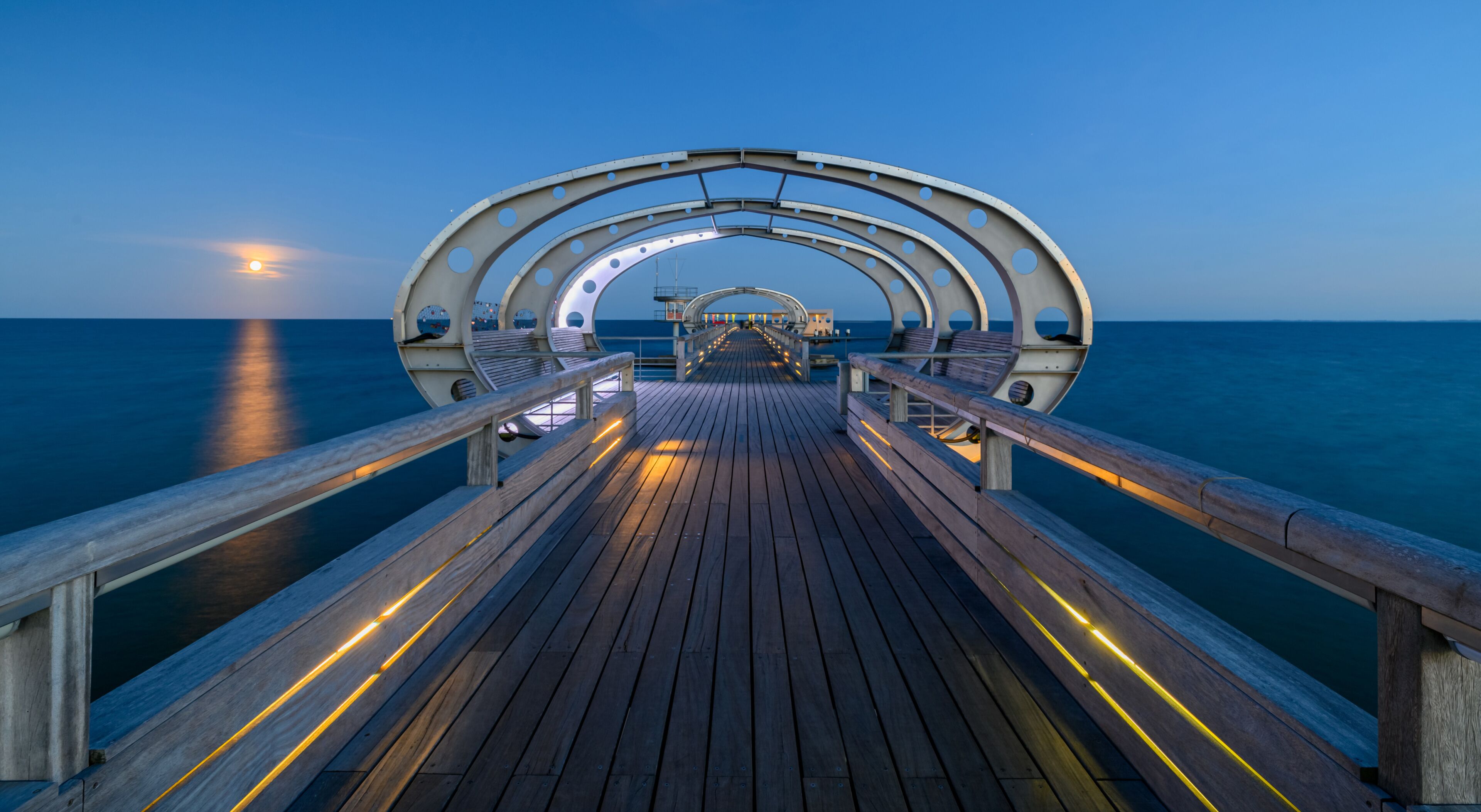 A wooden pier extending into the sea with a circular archway at the end.