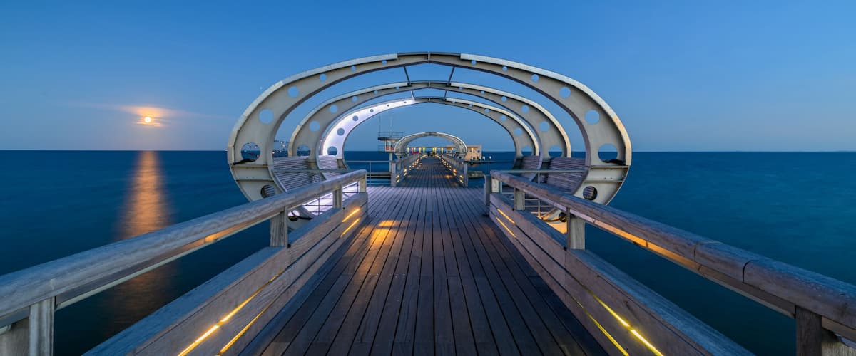 A wooden pier extending into the sea with a circular archway at the end.