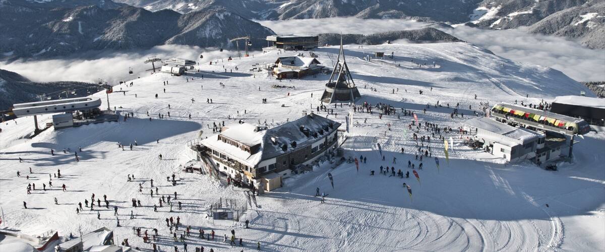 A snow-covered ski resort with a prominent church, ski lifts, and a mountain backdrop.