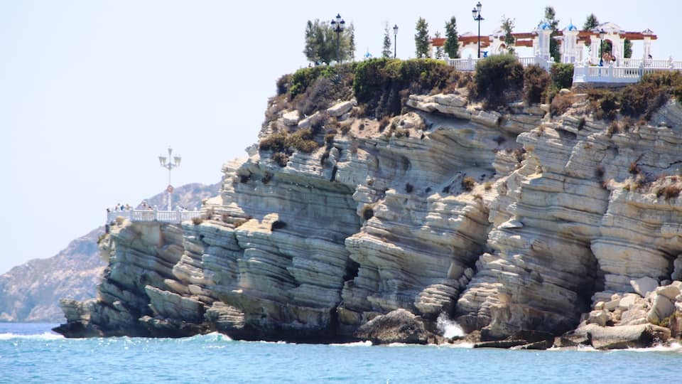 A rocky coastline with a white building on top, overlooking the sea.