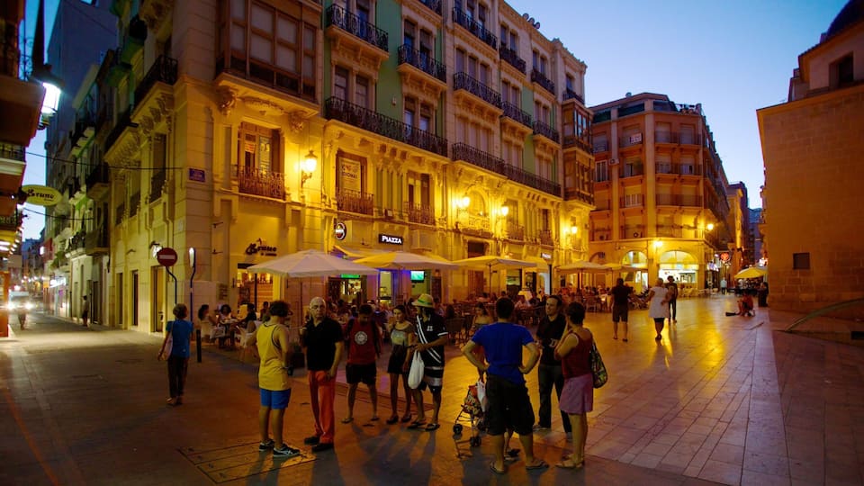 A bustling square with people walking and sitting at outdoor cafes, surrounded by historic buildings with ornate facades and balconies.