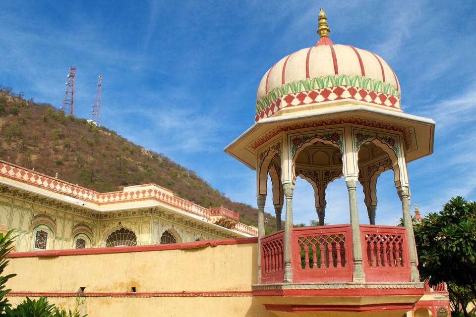 Een traditioneel Indiaas paviljoen met een koepelvormig dak en versierde bogen, gelegen voor een heuvel en een heldere blauwe lucht.