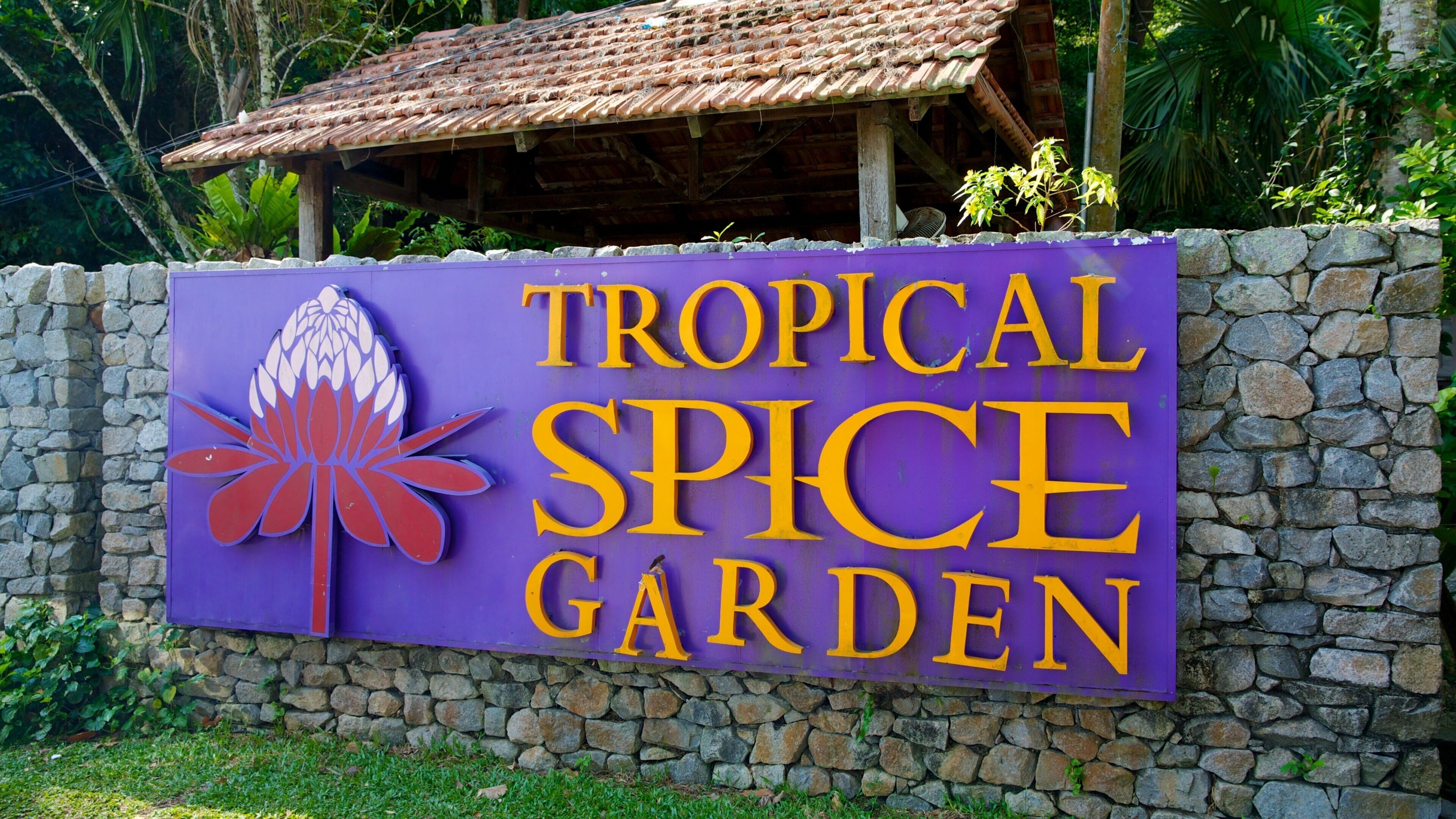 A sign for Tropical Spice Garden with a tropical flower design.