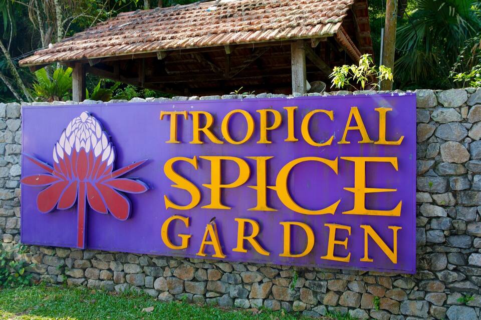 A sign for Tropical Spice Garden with a tropical flower design.