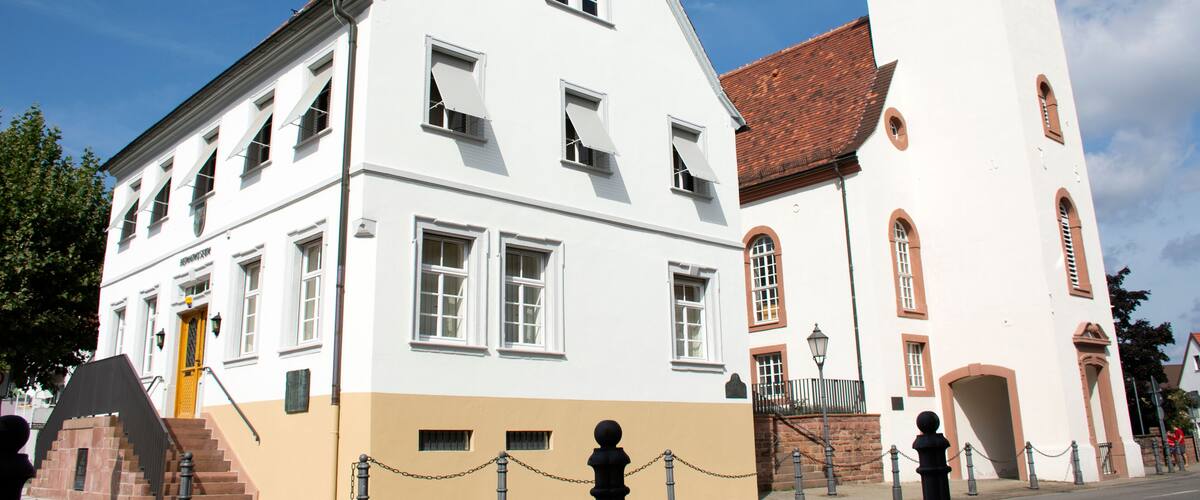 A historic building with a white facade and a red-tiled roof.