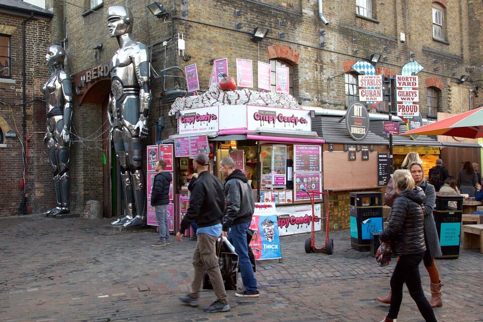 Un mercado de comida callejera con un puesto de dulces y una estatua de robot.