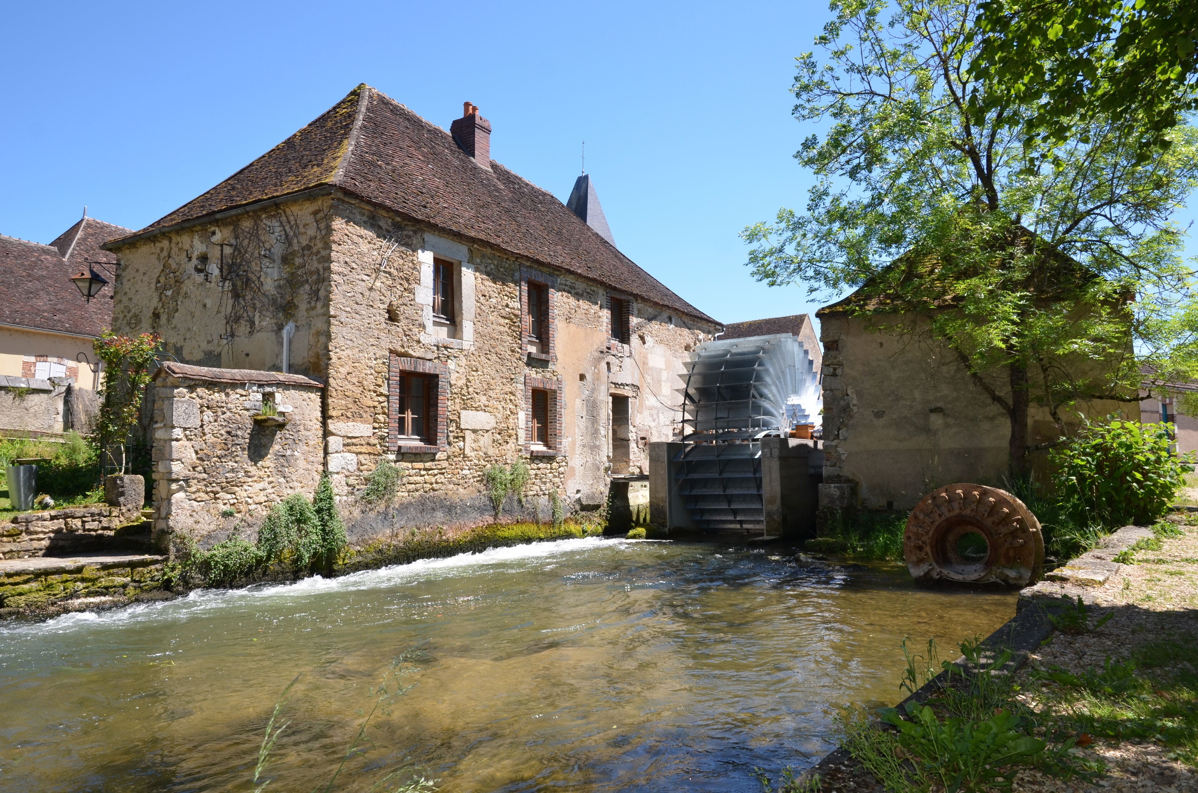 A stone building with a water wheel and a river.