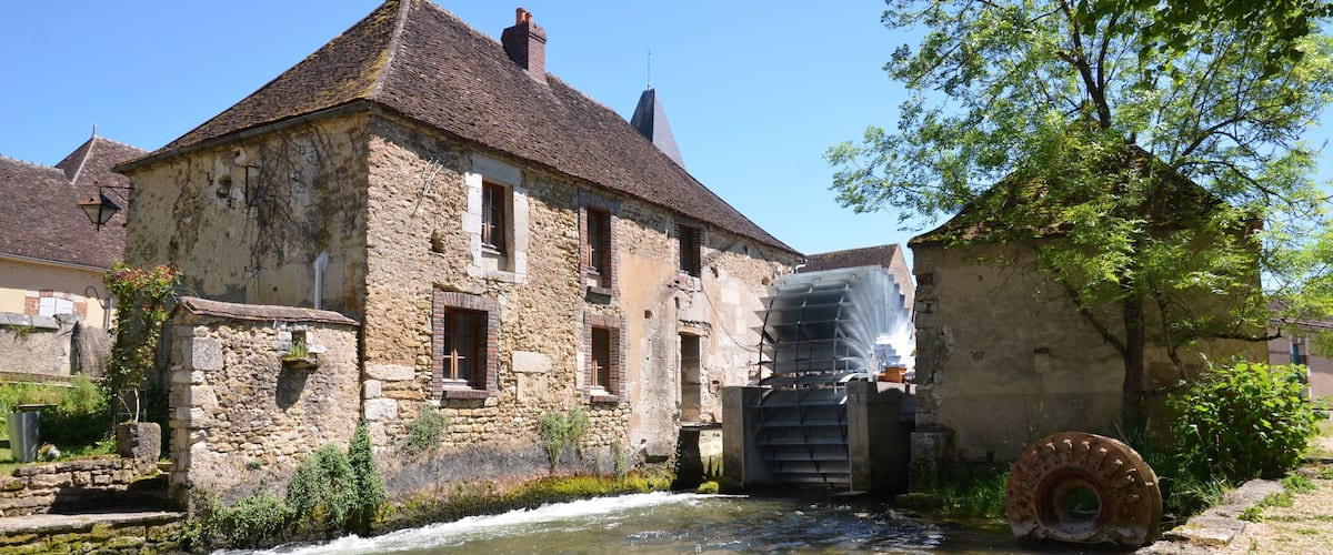 A stone building with a water wheel and a river.