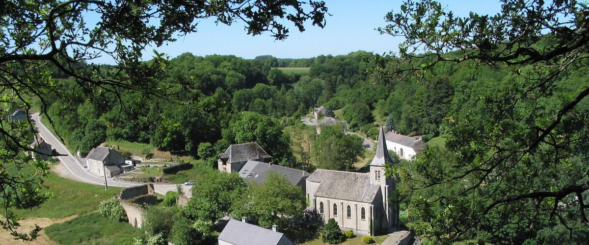 A village with a prominent church, several residential buildings, and lush greenery.