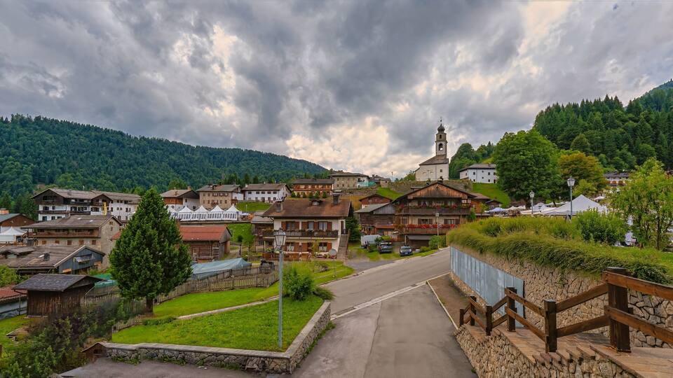 A village with traditional houses, a church, and a mountain backdrop.