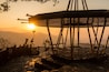 A wooden structure with a metal roof, set against a sunset with mountains in the background.