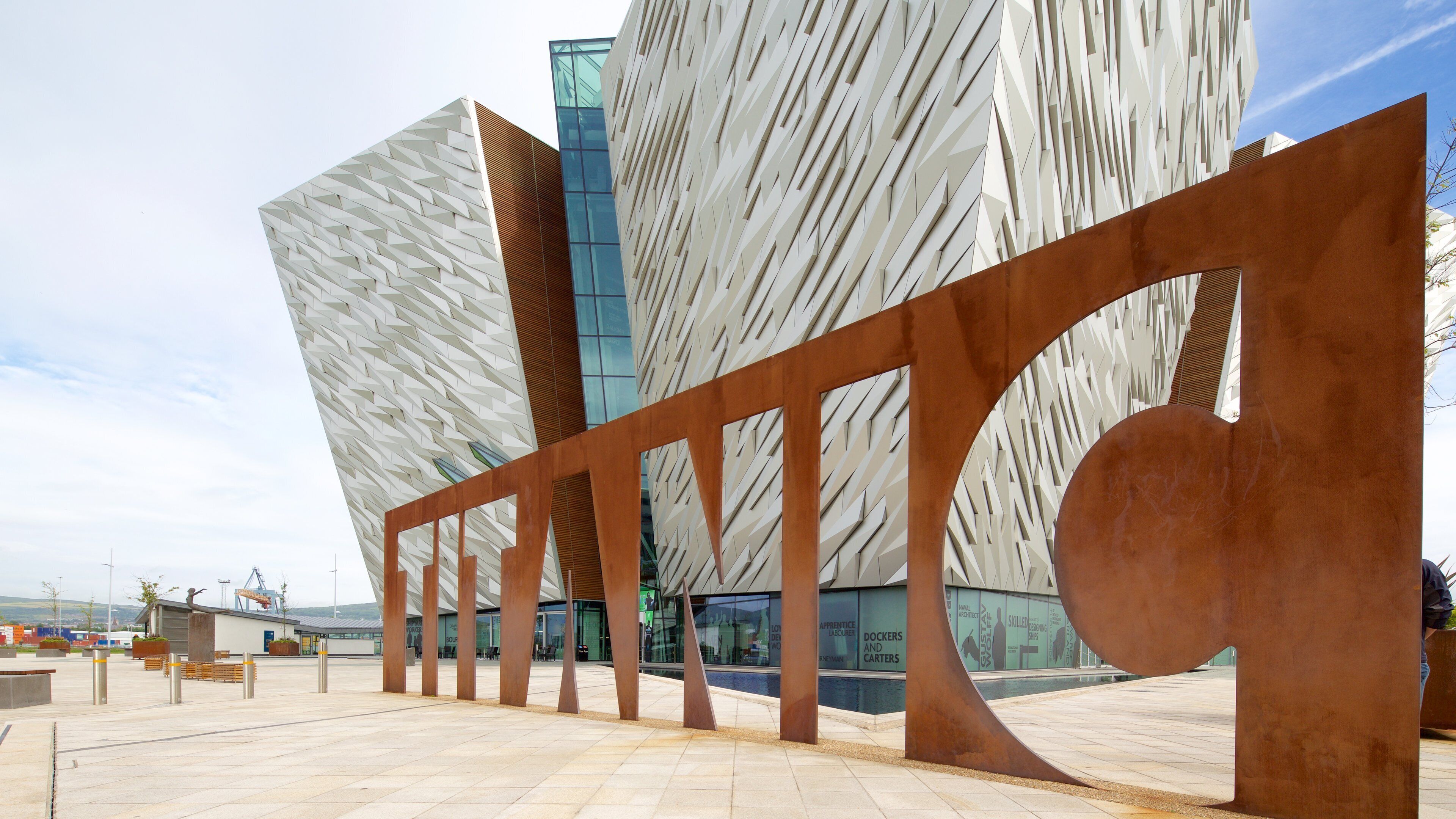 A modern building with a unique facade and a large metal sculpture in the foreground.