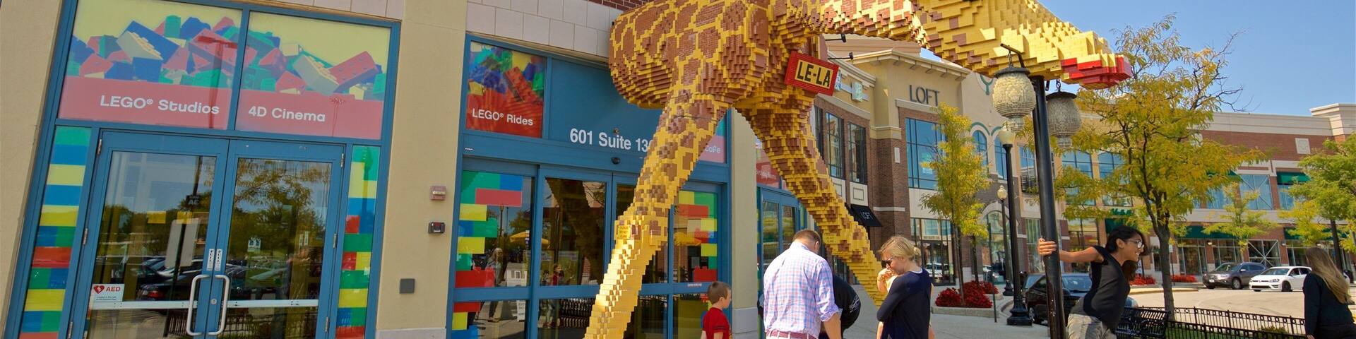 A LEGO giraffe sculpture in front of a LEGO Studios store.