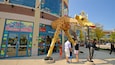 Eine LEGO-Giraffenskulptur vor einem LEGO Studios Geschäft.