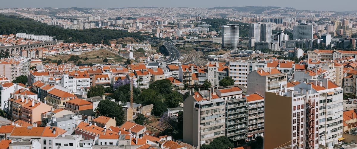 A cityscape with a prominent bridge, dense urban buildings, and a hilly backdrop.