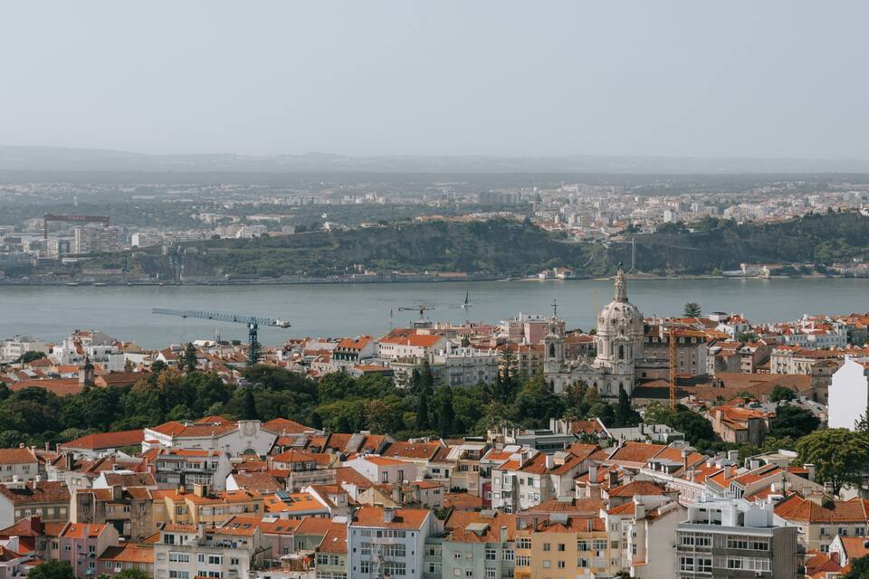 Paisagem costeira com uma catedral imponente, uma ponte e um rio.