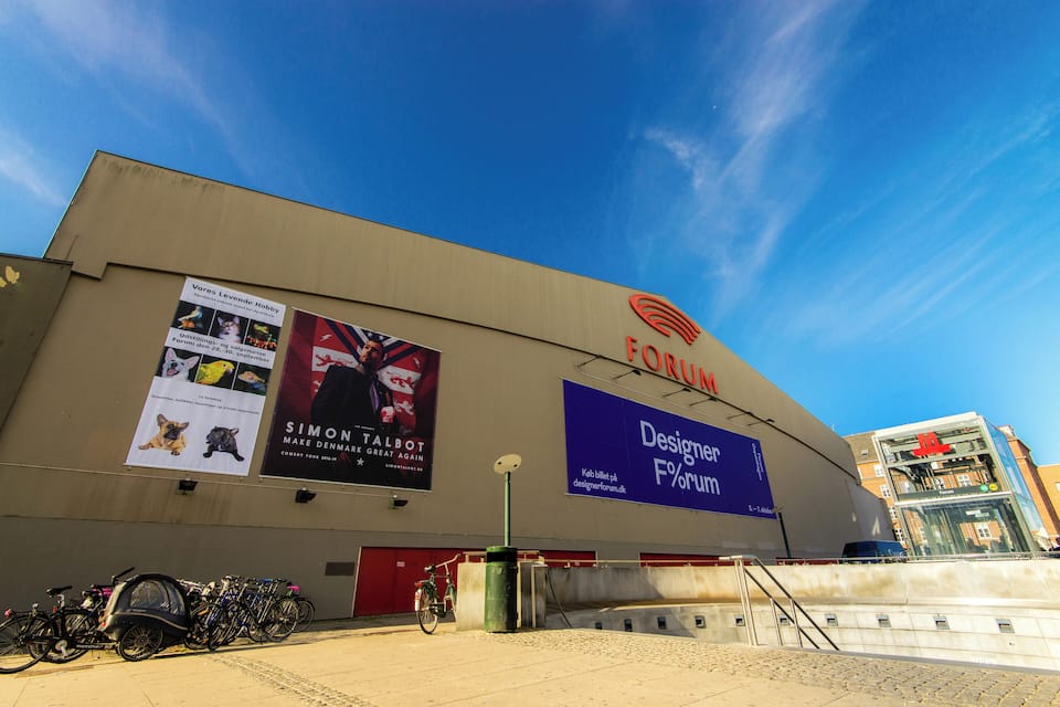 A building with a large sign reading "Forum" and another sign for "Designer Forum". There are bicycles parked in front.