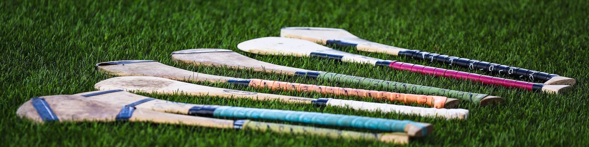 A bunch of camogie ash hurleys lie in the grass