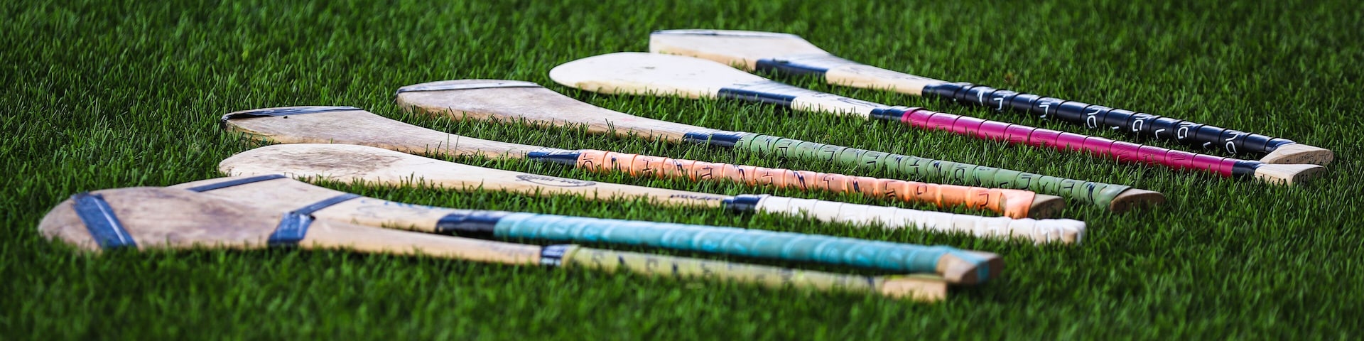 A bunch of camogie ash hurleys lie in the grass